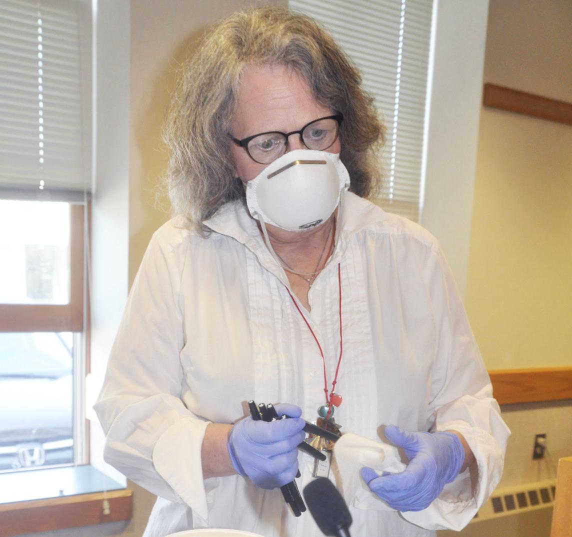 Poll worker sanitizes pens after each use on Election Day
